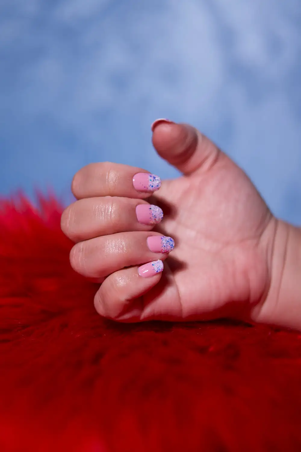 Uñas rosas con glitter y anillo plateado